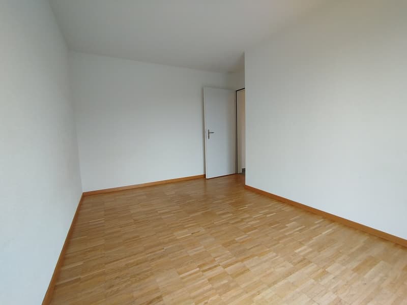 Empty room with white walls, wooden floor, closed door
