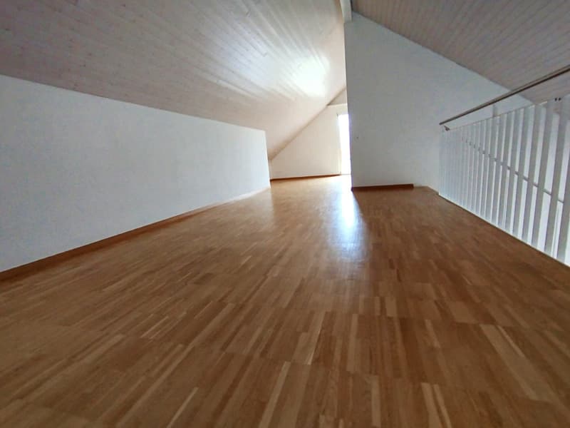 empty room, wooden floor, white walls, exposed wooden beams, steep slope ceiling