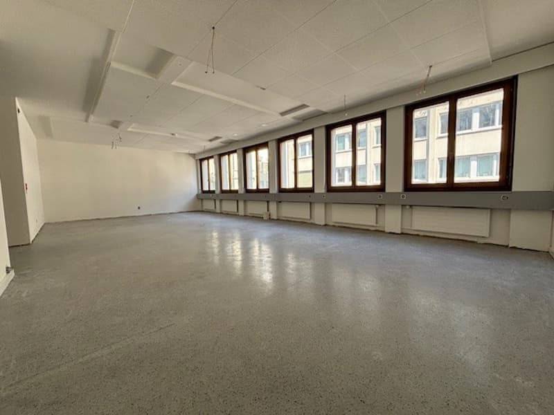 An empty room with windows on one side and white walls and ceiling