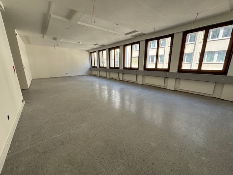 large open space, concrete floor, large windows, white walls, ceiling lamps