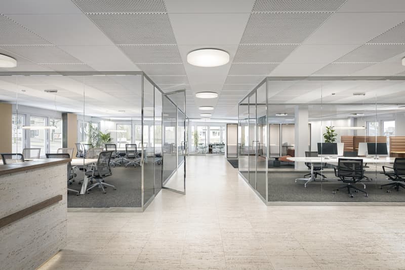 Glass walls, bright white ceiling, large reception desk, glass doors, office chairs and tables