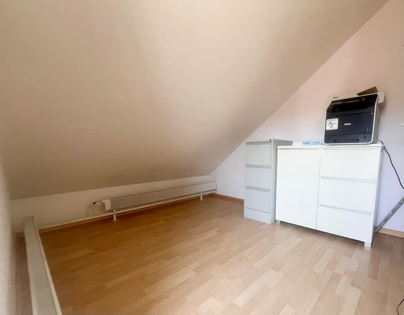 Attic room with hardwood flooring, white walls, a printer/scanner, and a white cabinet with drawers.