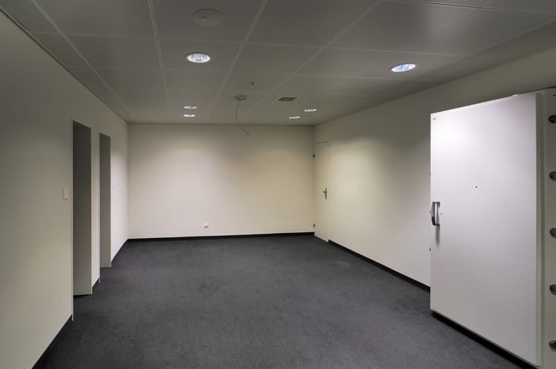 empty room, white walls, gray floor, recessed ceiling lights, door, electrical outlet