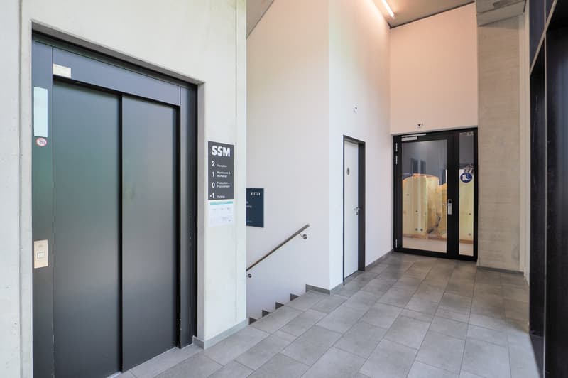 Tiled corridor, elevators, stairs, glass doors, signboard, parking information, reception area, warehouse information