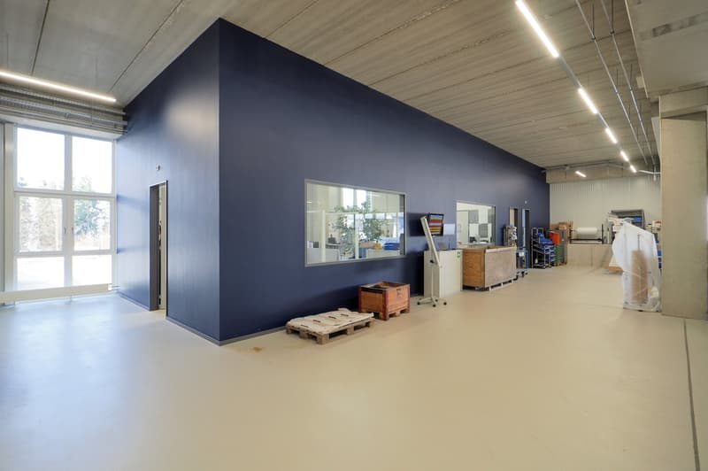 Empty room with blue wall, white floor, a window, and various equipment and items in the room