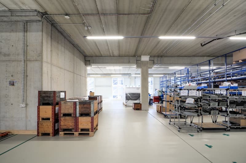 concrete walls, wooden pallets, metal storage units, overhead lighting, clean white flooring