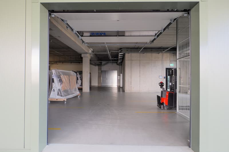 Large, open garage with concrete floor, forklift present, yellow markings on the floor.
