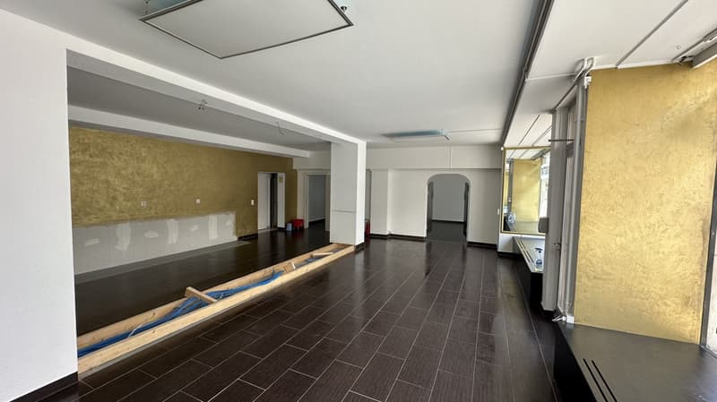 modern empty space with wooden flooring, gold wall panels, high ceiling, windows, wooden frame with blue cables