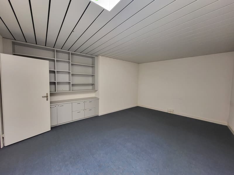 Empty room, gray floor, white walls, ceiling with panels, white door, built-in cabinets, built-in shelves
