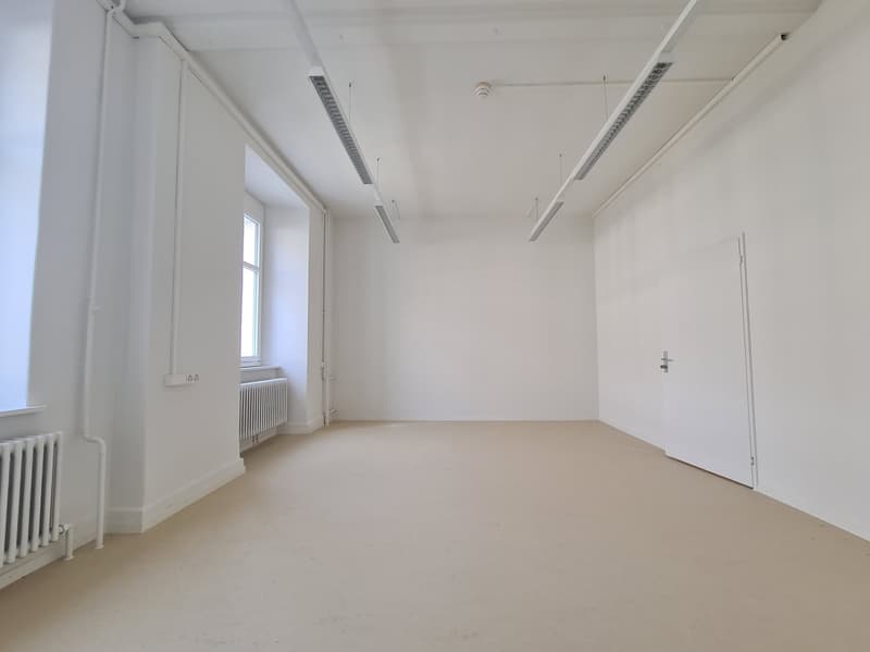 empty room with white walls and ceiling, two radiators, and a window with a door next to it