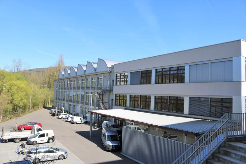 commercial building, multiple floors, glass windows, large parking area, many vehicles parked