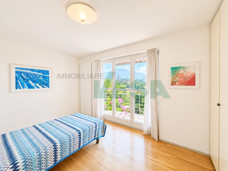 una camera da letto con letto, ampia finestra, porta e balcone / a bedroom with a bed, large window, door and balcony