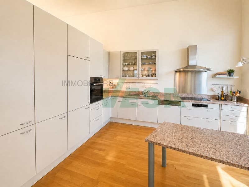 una grande cucina con armadietti ed elettrodomestici bianchi e pavimento in legno / a large kitchen with white cabinets and appliances and a wooden floor