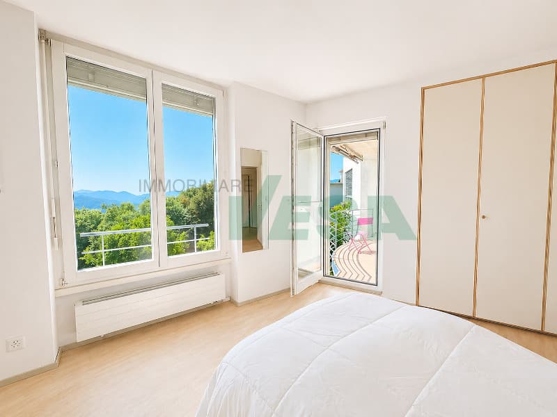 una camera da letto in un appartamento moderno con una grande finestra e una porta / a bedroom in a modern apartment with a large window and door