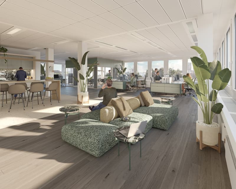 Open plan office with a kitchen area, a lounge area with a couch, a desk area with chairs and computers, and a large window with a view of the outside.
