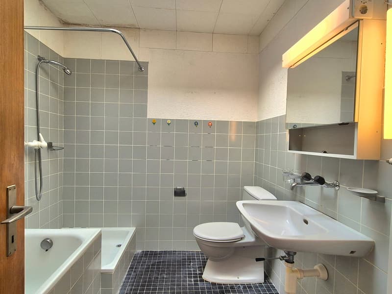 Tiled walls and floor, bathtub, toilet, sink, overhead shower with a shower curtain