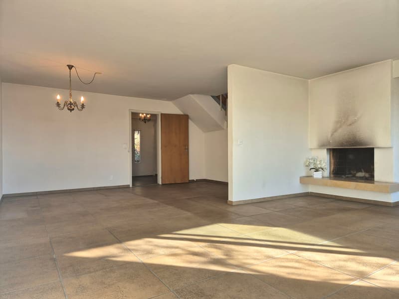 Empty room, fireplace, chandelier, white walls, brown tiled floor