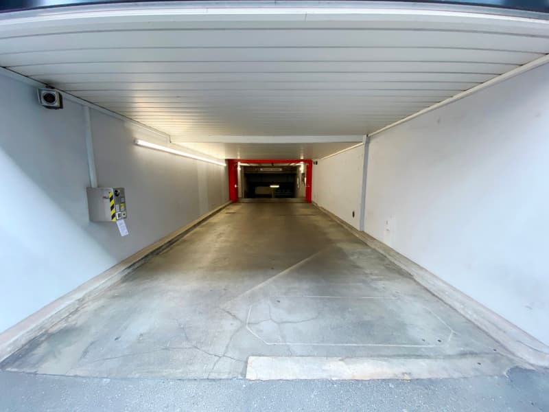 Empty parking lot, white walls, concrete floor, surveillance camera, fluorescent lighting