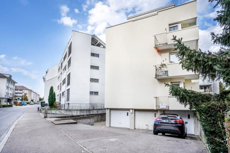 Modern white building, 3 floors, garage, balconies, car parked in front