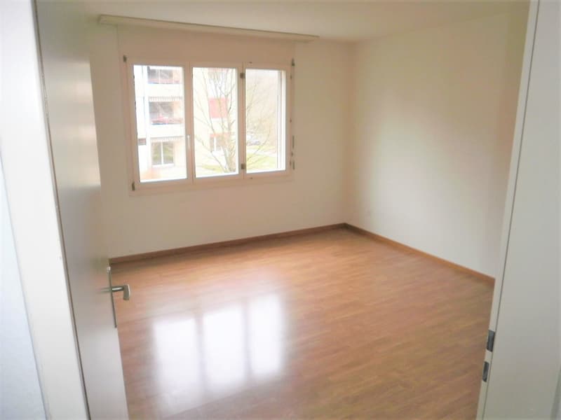 Empty room, wooden floor, white walls, large window with a view outside