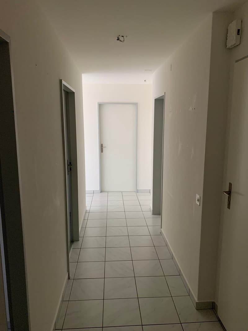 empty hallway, white tiles, white walls, ceiling mounted light, two doors