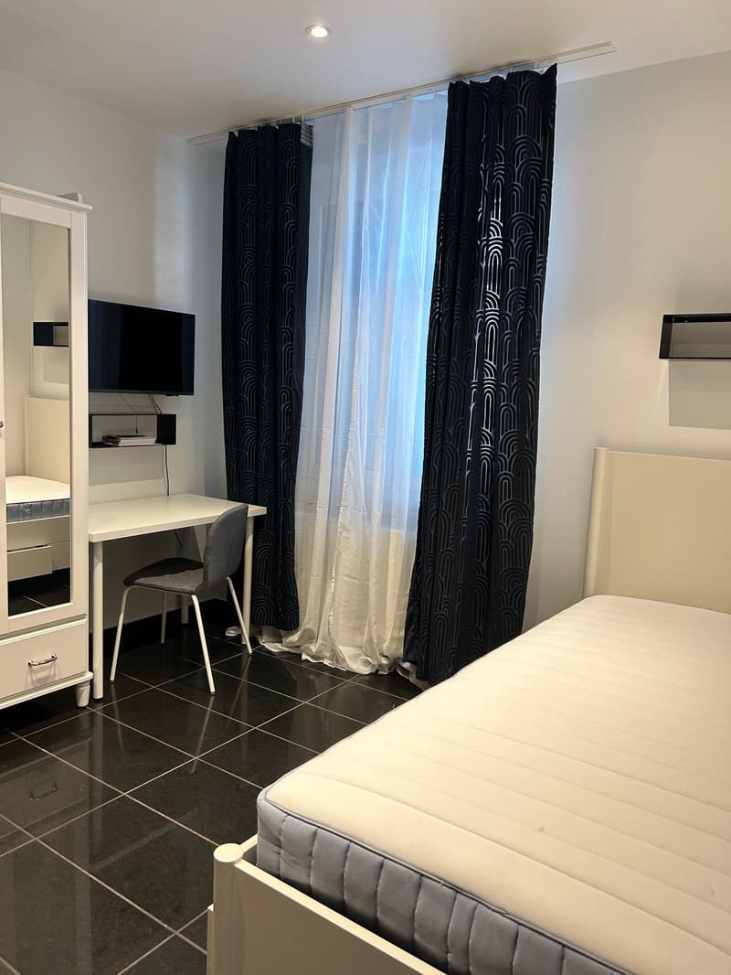 small bedroom with desk, chair, bed, and mounted TV