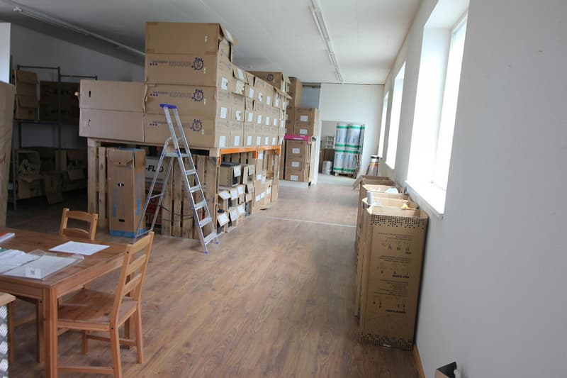 Empty room with several stacked boxes, ladder, desk, two chairs