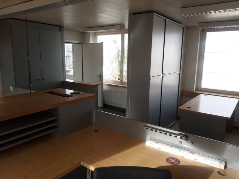 Office room with wooden desks, gray cabinets, windows, and a radiator.
