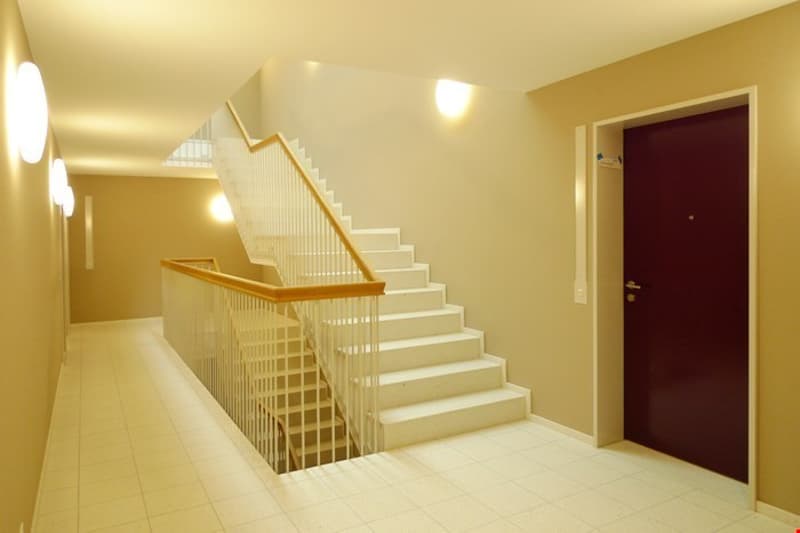 White tiles flooring, white marble steps, golden metal handrail, burgundy wooden door, lights in the wall