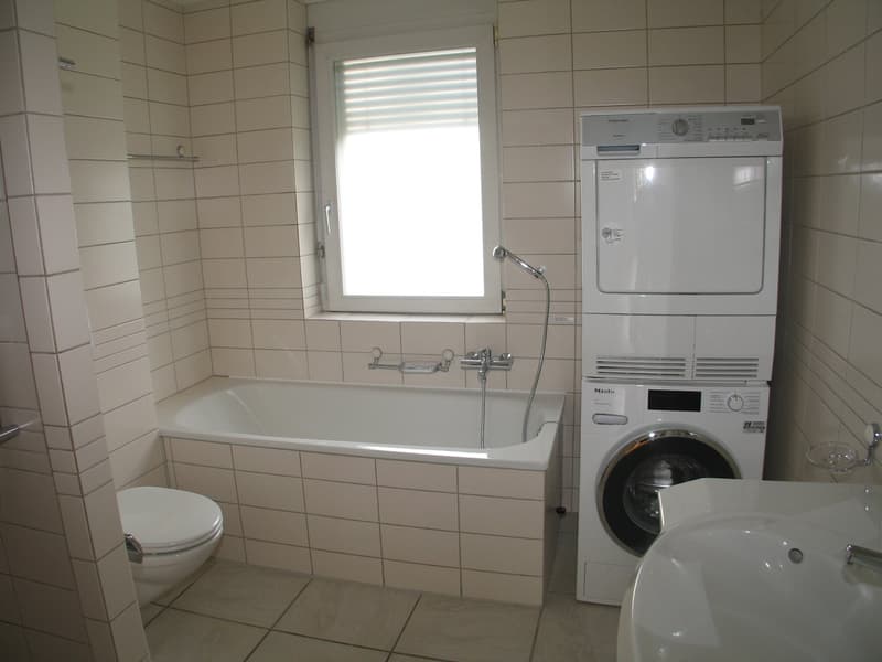 Bathroom with bathtub, washing machine, dryer, toilet, and sink