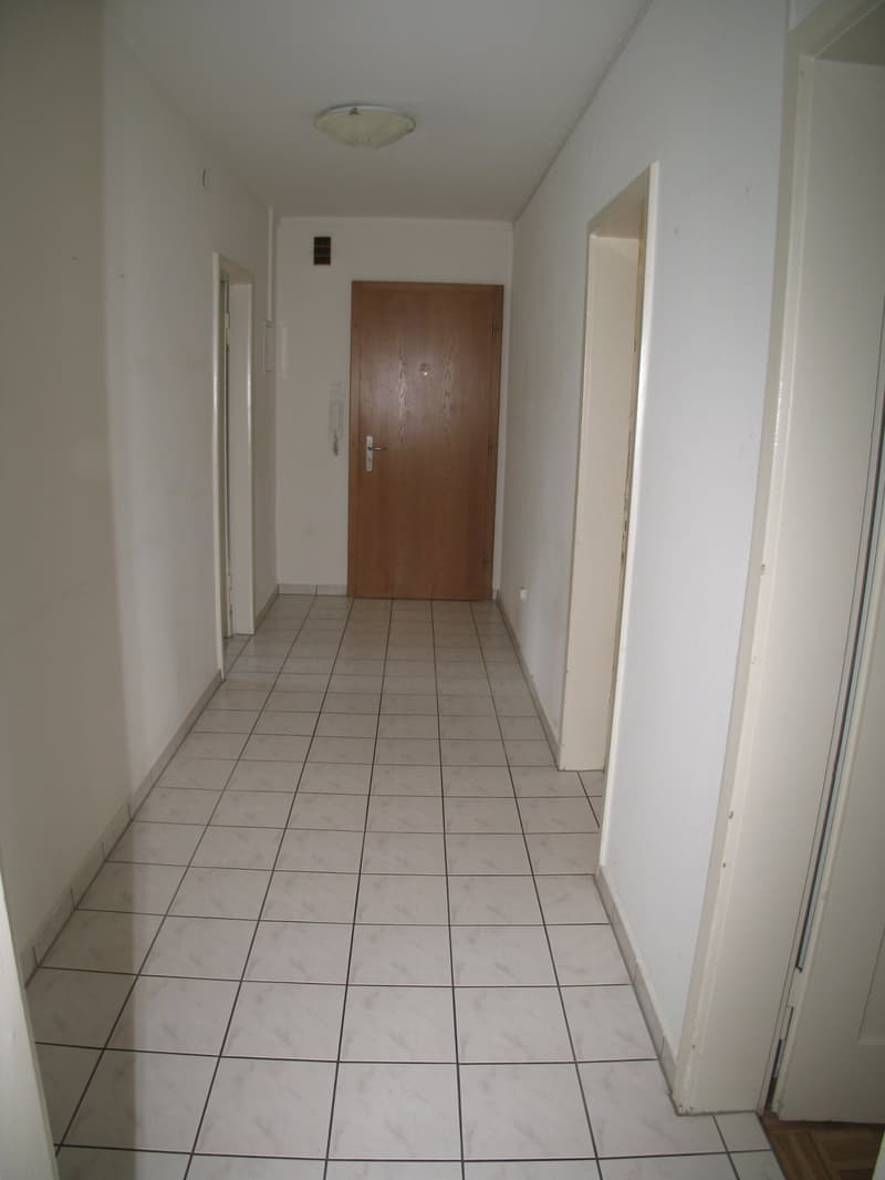 tiled corridor, brown door, white walls, hallway light