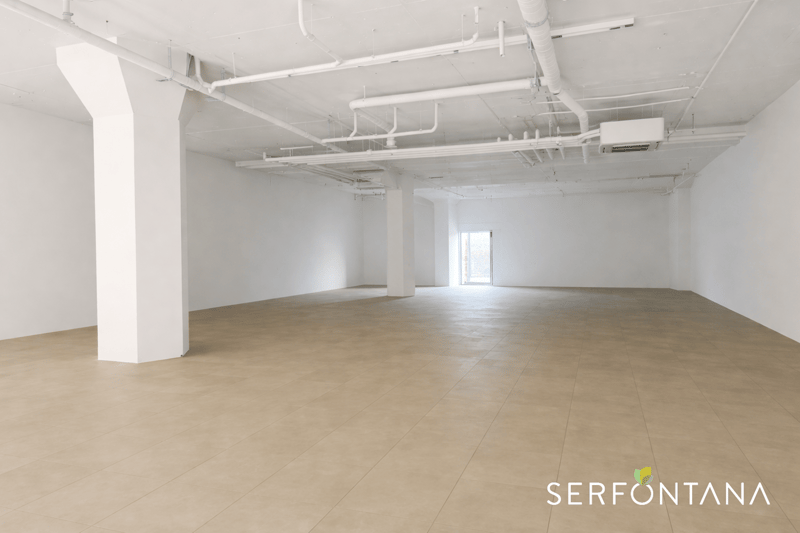 Empty commercial room with exposed ducting, large open space, no furniture, white and beige tiles
