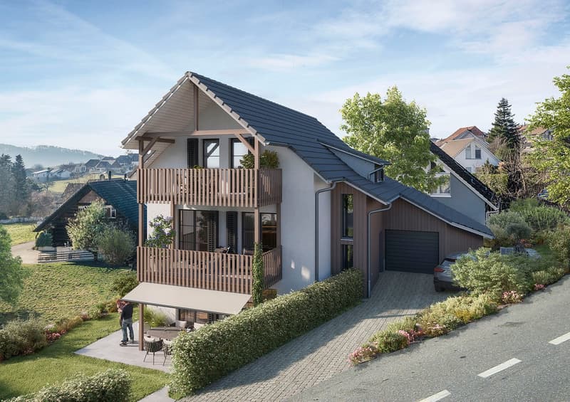 2-story house with a gable roof, gray exterior walls, and a wooden balcony. The house has a garage and is surrounded by landscaped gardens and trees.