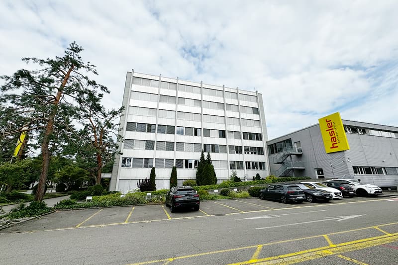 white building, many windows, cars parked, logo on side