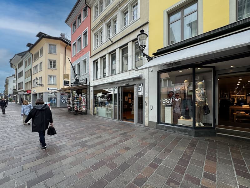 urban street, brick flooring, storefronts, people walking, street lamp