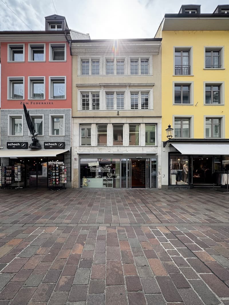 three buildings along the street, brick sidewalk, glass doors, white awnings, storefronts