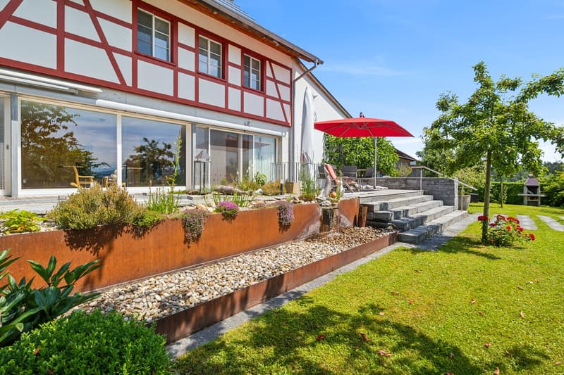 white and red exterior, large glass windows, red umbrella, red brick stairway, landscaped garden