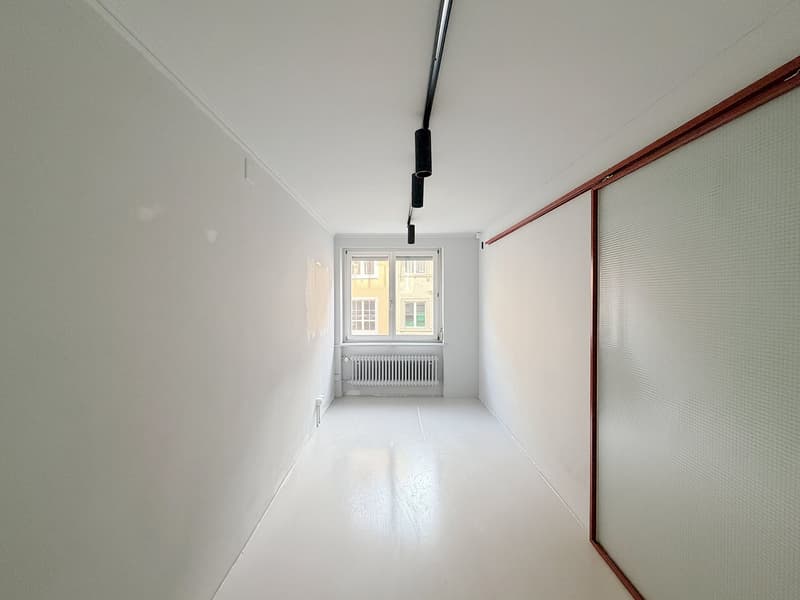 Empty room, white walls, white floor, window, radiator, track lighting