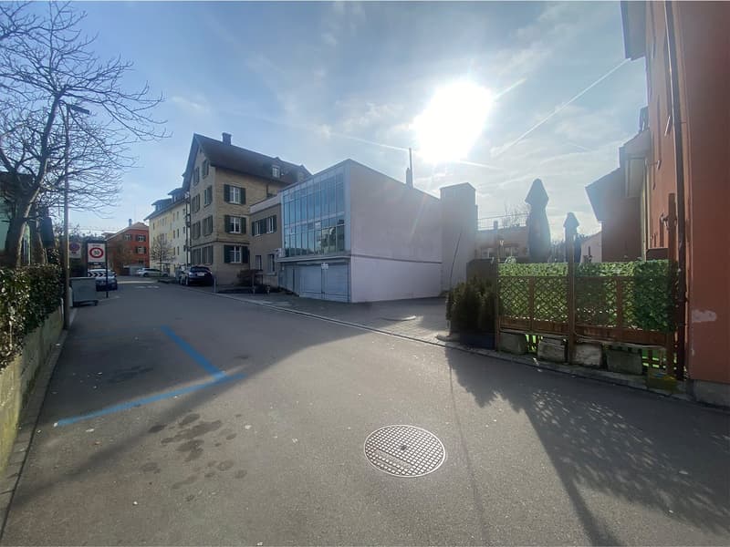 Empty street with two garages on the left, surrounded by buildings
