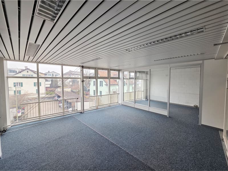 Empty room, carpet flooring, large windows, balcony, bright lighting