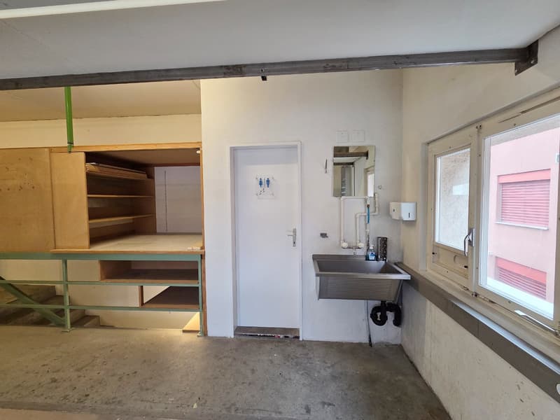 small room with cabinet, sink, toilet sign, white walls, metal railings