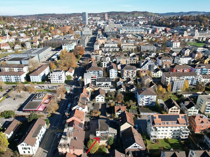 Urban landscape with various residential buildings, solar panels, greenery, parked cars in a city setting.