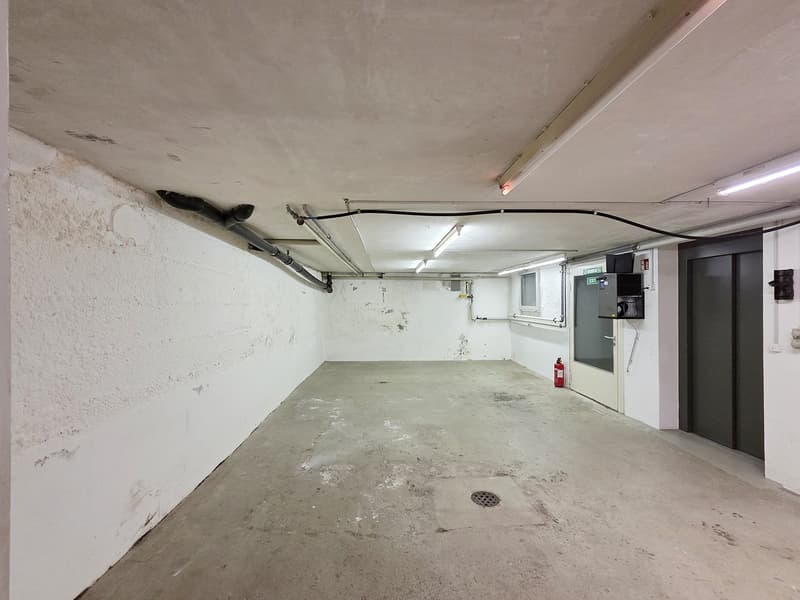 Empty basement, exposed concrete walls, ceiling lights, drainage holes