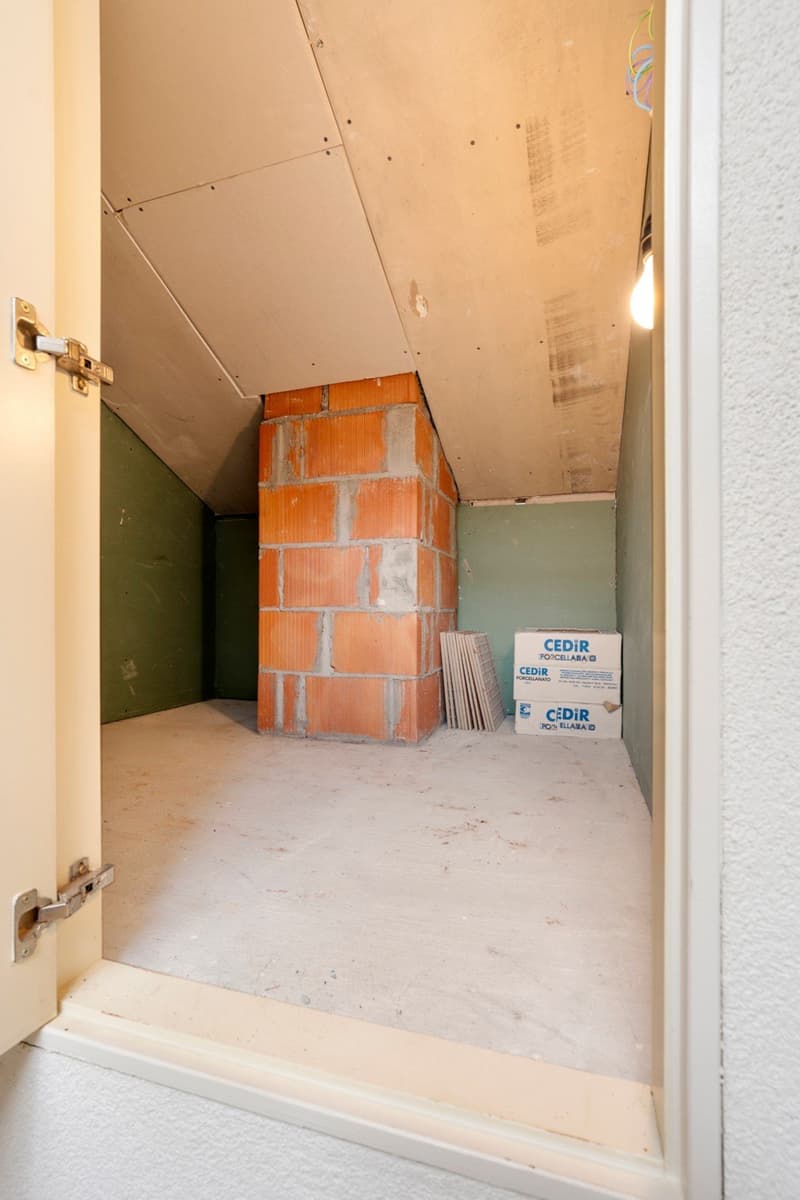 Small room with unfinished walls, brick pillar, boxes of tiles, open door