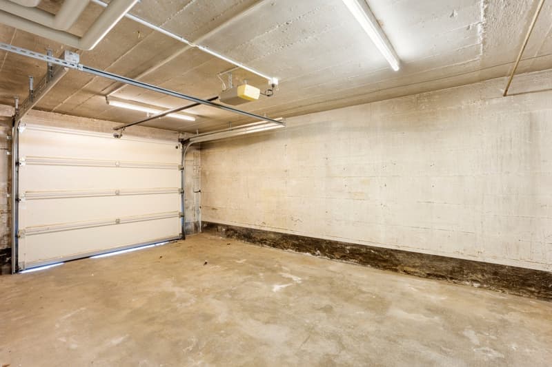 Empty garage with white walls, concrete floor, and a white garage door.