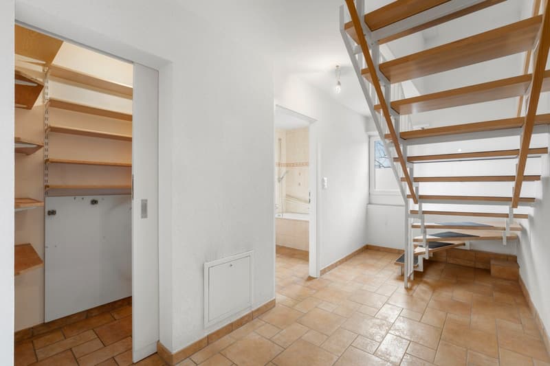 empty room, wooden stairs, tiled floor, white walls, open closet, bathroom with bathtub
