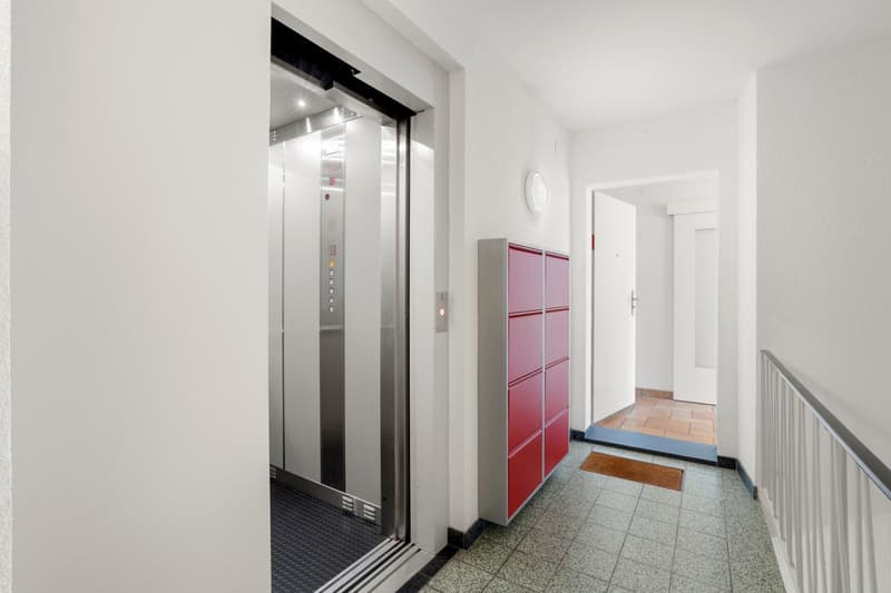 elevator, red lockers, tiled floor, white walls, open door