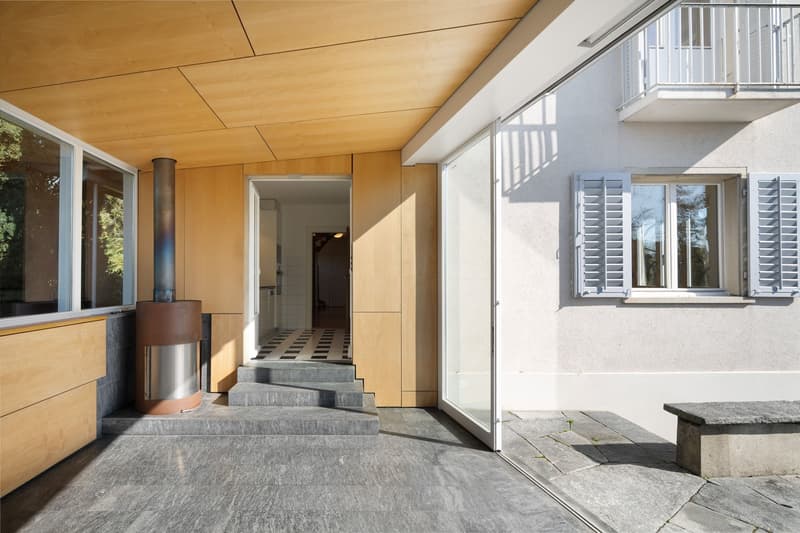 modern architectural design with wooden panels, stone floor, open door, glass windows, balcony, modern outdoor stove