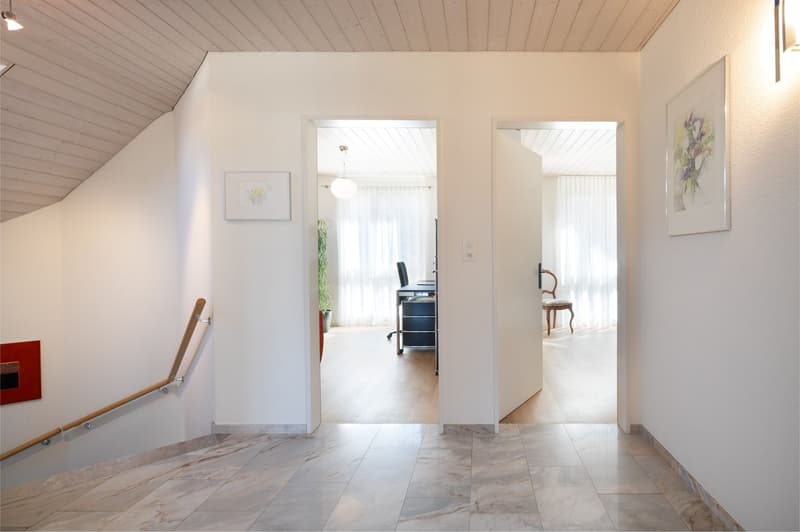 marble floor, white walls, wooden handrail, two open doors, picture frames, potted plant, desk, chair, light