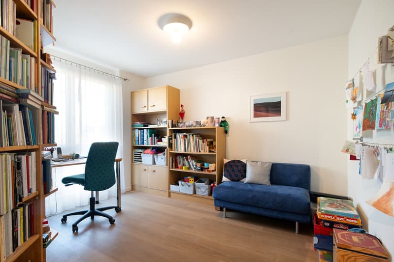 study room with desk, chair, bookshelves, couch, toys, picture frame